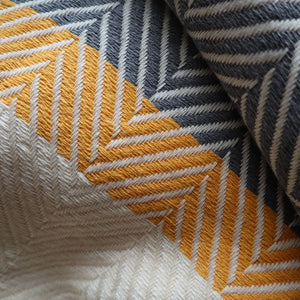 alt="close up detail of mustard grey herringbone throw blanket. Made by Living Roots, available from Bramble and Fox UK hygge homewares."