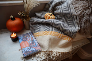 alt="cosy hygge flatlay featuring scandi mustard grey herringbone blanket, a spotter's guide to countryside mysteries and hygge homewares. Available from Bramble and Fox UK hygge shop."