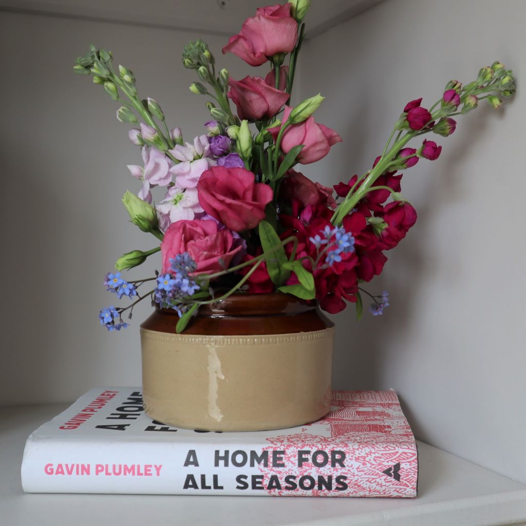 antique pearsons of chesterfield stoneware jar filled with blooms. It rests on a copy of A Home for All Seasons by Gavin Plumley. Jar available from Bramble and Fox UK hygge homeware and gifts