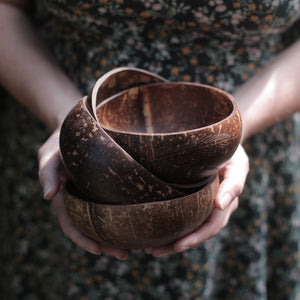 alt="hands holding a pile of coconut shell bowls. Available from Bramble and Fox Uk hygge homeware shop"