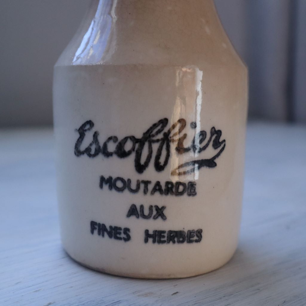 alr="close up of typography on vintaage stoneware mustard jar. Typography reads:  Escoffier moutarde aux fines herbes. Available from Bramble and Fox Uk cosy handmade and vintage homewares"