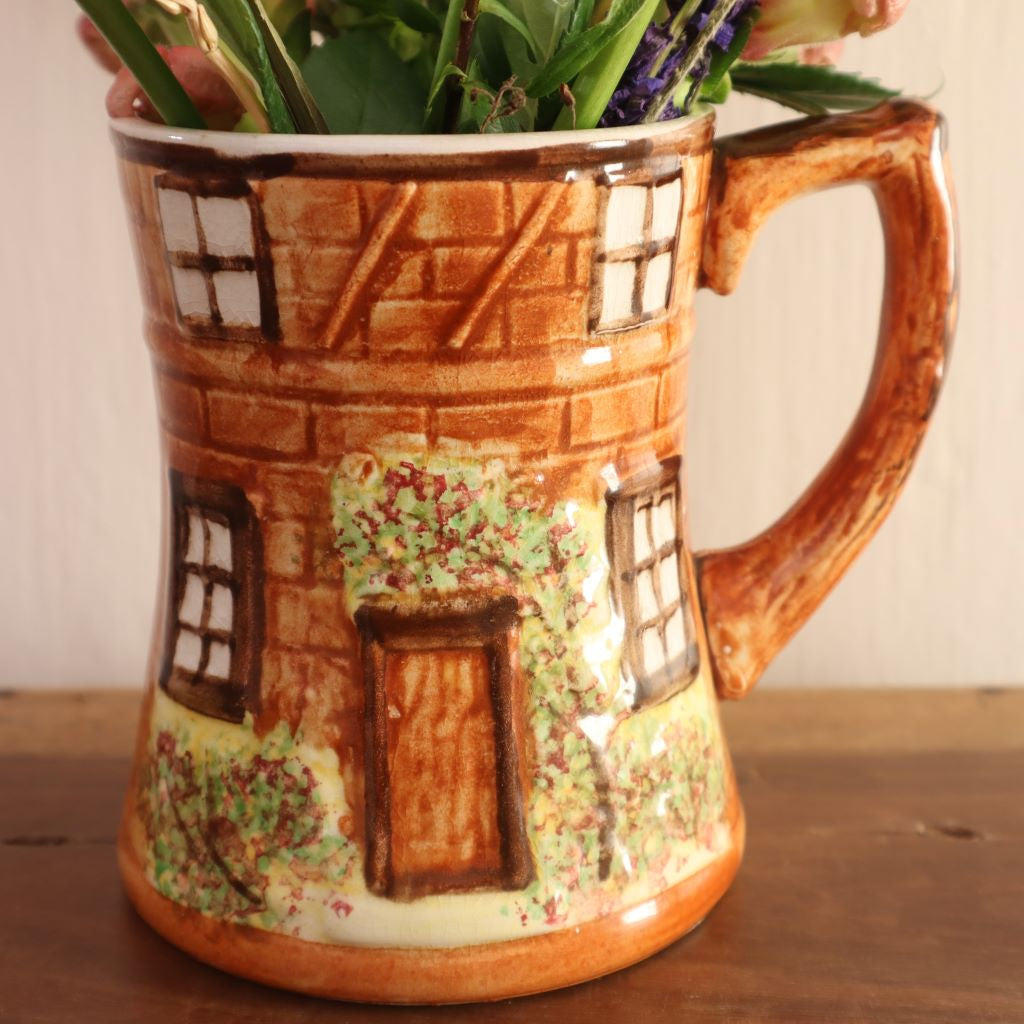 alt="close up of Price Kensington cottage mug featuring mullion windows, climbing roses over the door and a rustic handle resembling a tree trunk. Available from Bramble and Fox UK cottagecore home decor shop"