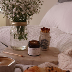 alt-"In the Dawn Light aromatherapy candle by Ochre and Flax. Hygge candle scene on bed with Numol jar of matches and kilner jar of flowers. Candle available from Bramble and Fox UK hygge shop"