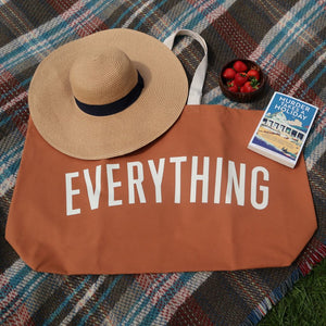 alt="flatlay feaaturing book Murder Takes a Holdiay crime collection along with a sun hat, a bowl of strawberries, a tartan picnic blanket and an oversized canvas tote bag emblazoned with EVERYTHING. All available from Bramble and Fox UK hygge cottagecore shop"