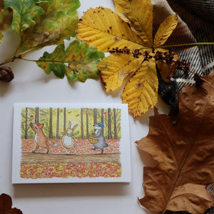 alt="Autumn walk greetings card surrounded by autumn leaves and foliage. Available from Bramble & Fox UK hygge shop"