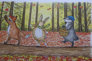 alt="close up of Autumn Walk by Kerry Dilks, featuring a wind in the willows-esque fox, rabbit and badger catching the autumn leaves and woodland foraging. Available from Bramble and Fox UK hygge shop"