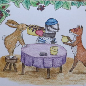 Blackberry Crumble greetings card by Kerry Dilks. Features a lovely brambly border and a Wind In the Willows-esque scene of badger in a pinny holding the crumble aloft, while rabbit sneaks a sniff and fox brandishes a jug of custard. Available from Bramble and Fox UK hygge shop."