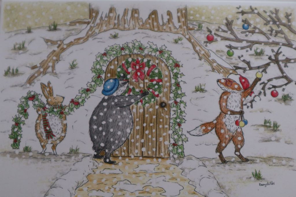 alt="close up of Christmas Decorating Christmas card by Kerry Dilks. Features a snowscape of badger, fox and rabbit decorating their woodland home for Christmas. Available from Bramble and Fox UK hygge shop"