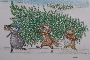 alt="close up of Pick a Tree christmas card by Kerry Dilks. Featuring a cosy snowy scene of badger, fox and rabbit lugging a ginormous christmas tree through falling snow. Available from Bramble and Fox UK hygge homewares gifts."