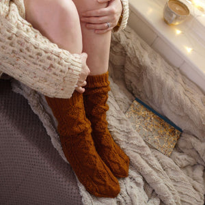 alt="woman's legs in gingerbread coloured knitted socks. A marbled paper journal is next to her. Available from Bramble and Fox UK hygge homeware and gifts"