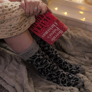 alt="woman's legs in cosy fair isle hand knitted boyfriend socks holding Hercule Poirot's Christmas book. Socks available from Bramble and Fox UK hygge homewares and gifts"