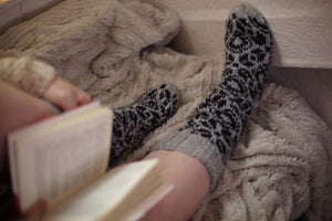 alt=" woman's legs in cosy hand knitted grey and indigo fair isle boyfriend socks. Available from Bramble and Fox UK hygge homewares and gifts"