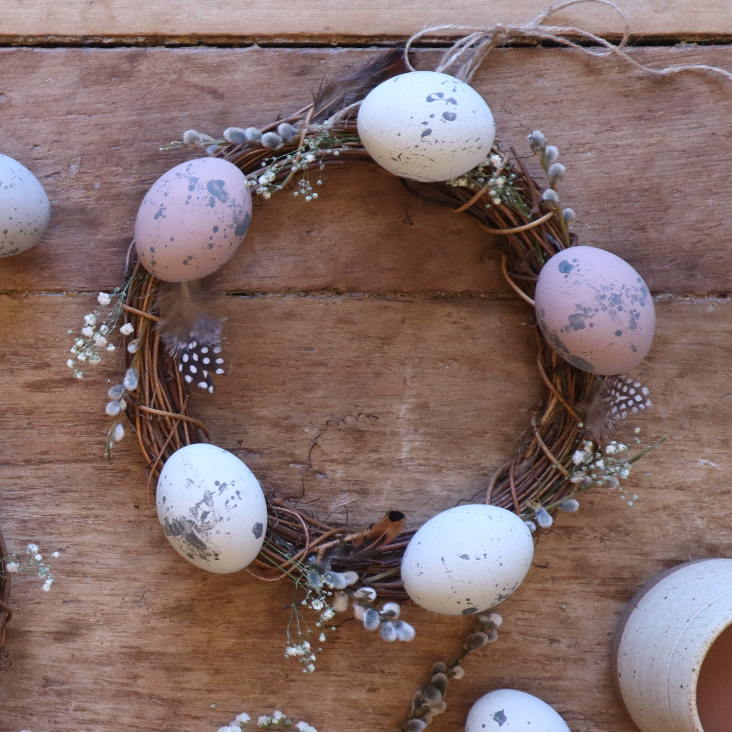 alt="rustic spring wreath featuring handpainted speckled eggs. cruelty free feathers and foraged pussy willow. Wreath available from Bramble and Fox UK hygge homewares and gifts"