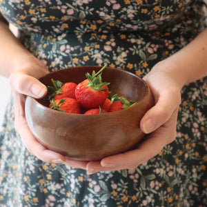 alt="woman's hands holding a wooden bowl of strawberries. Available from Bramble and Fox UK hygge cottagecore shop"
